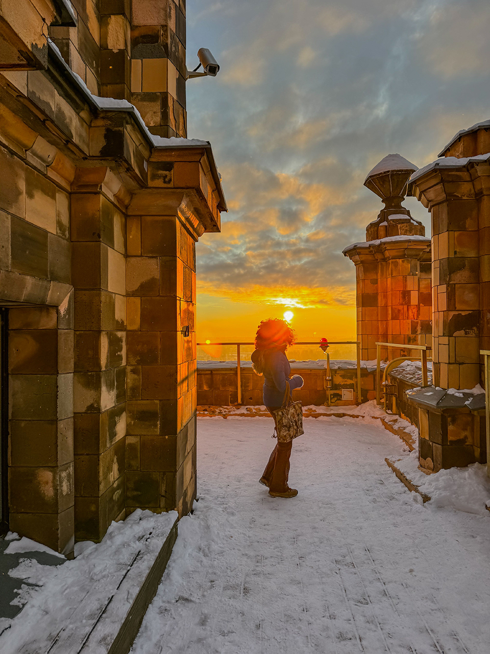 girl on a building covered in snow with sunset behind her