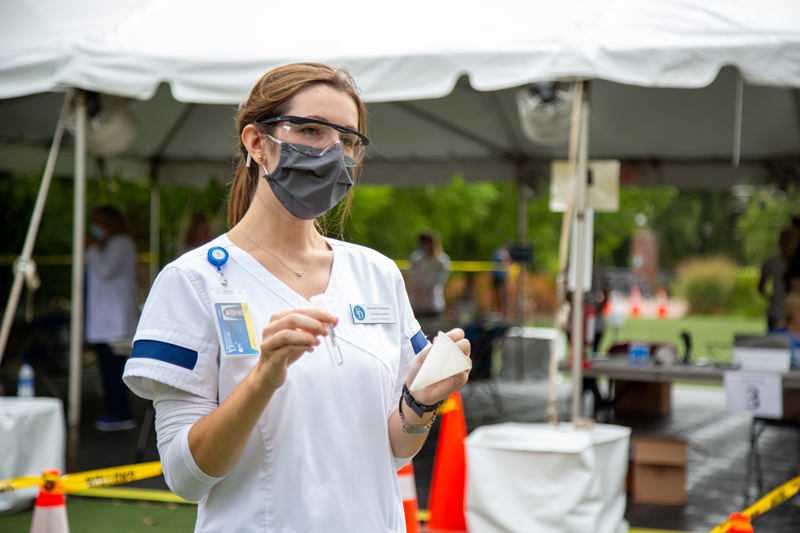 Nurse holding a pipette and cup during a COVID testing event