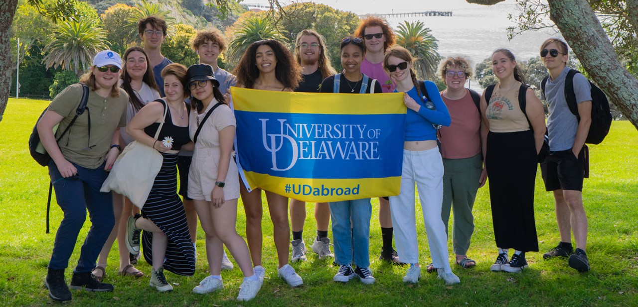 Study Abroad Students pose with a UD flag.