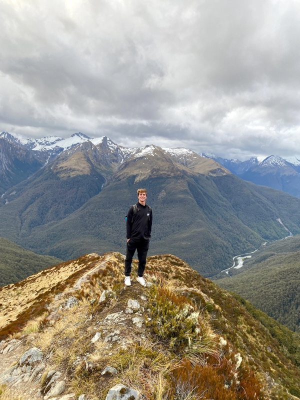 Student abroad standing on a mountain top.