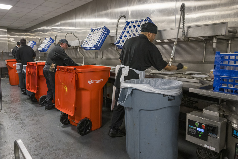 Dining Services workers separate organic materials — food waste — into 64-gallon orange “toters,” which will be picked up by UD partner Natural Upcycling for conversion to fertilizer and/or energy production.