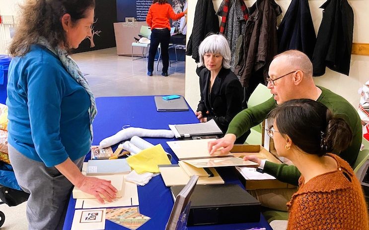 4 people at a blue table with papers 4 people at a blue table with papers