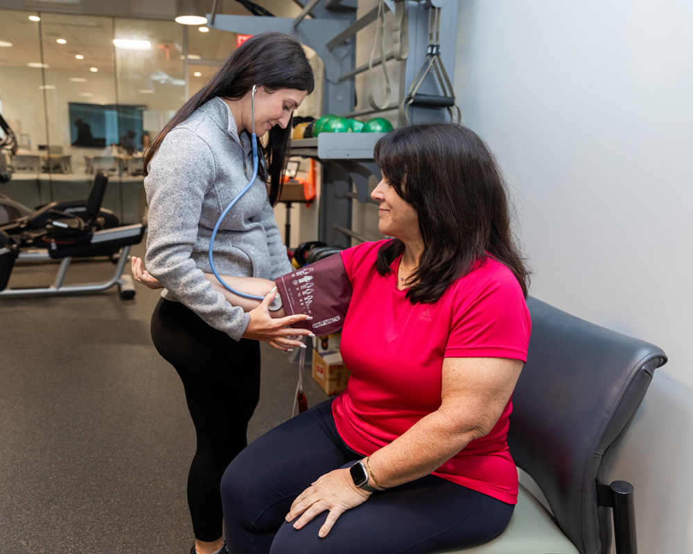 Exercise Physiologist taking biometric measurements of a mid-life adult in a gym setting