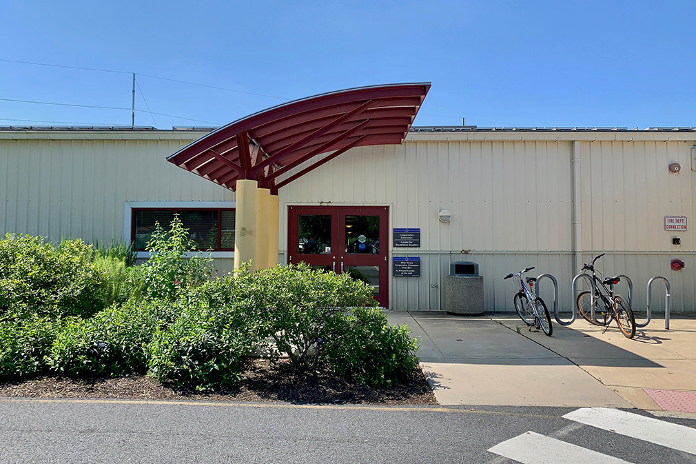 A photo of the front of the New Castle County Extension building with green shrubs.