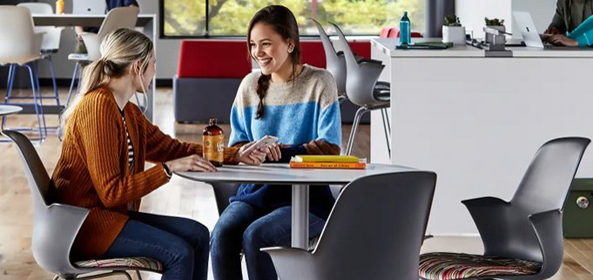 Two female students conversing at a table