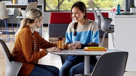 Two female students conversing at a table