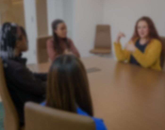 students sit at a table, talking with a CCSD staff member