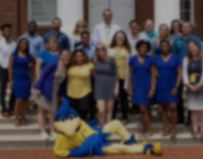 RLH staff pose on the steps of Memorial Hall while YouDee lounges on the ground in front