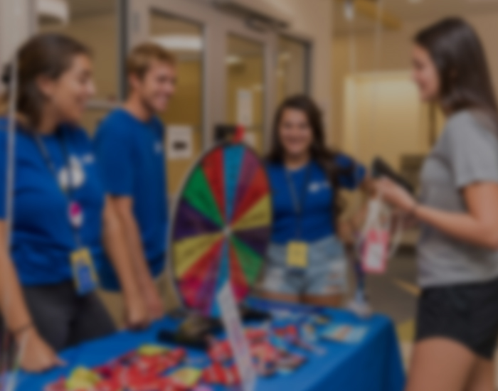 students gather around a prize wheel inside a residence hall