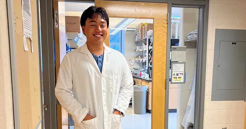 Student in lab coat standing in the laboratory doorway