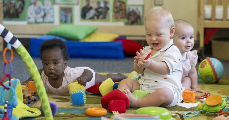 three babies playing with toys in a classroom setting