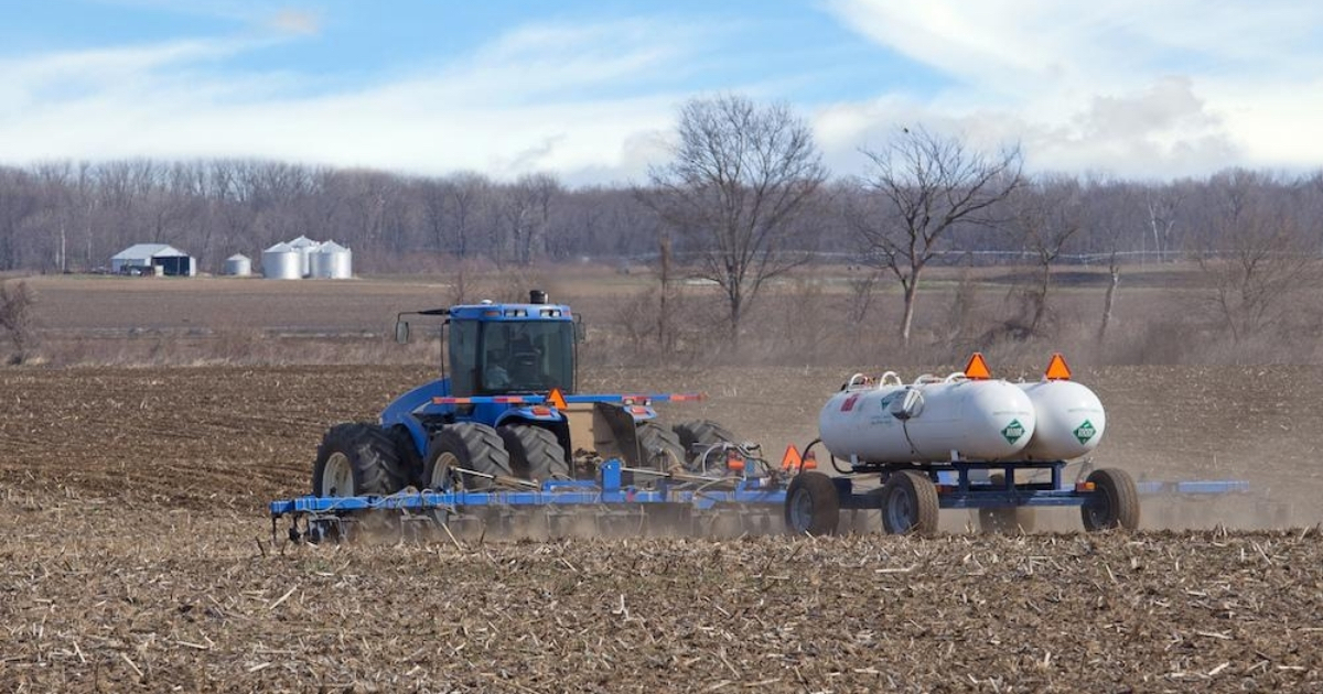 A blue tractor applying nutrients to a field A blue tractor applying nutrients to a field