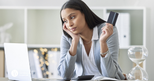 A woman worried looking at her laptop while holding her credit card