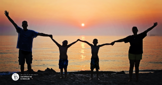 a family of four on a shore at sunset holding hands