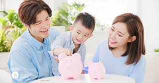 Two parents with their child putting money in a piggy bank