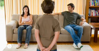 Two parents on the couch facing a child as he listens