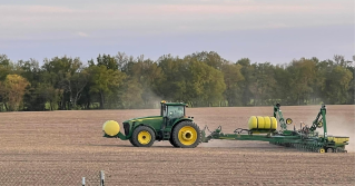 A tractor in a field planting corn