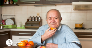 A male senior eating an orange