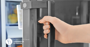 A close up of a hand opening a refrigerator door