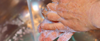 A close up of hands being washed in a sink