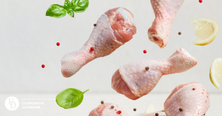 An image of raw chicken drumsticks dropping from above with herbs