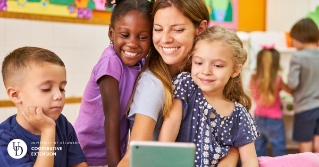 A teacher looking down at a cell phone with children