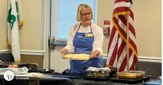 A health and well being educator holding a dish of cooked food