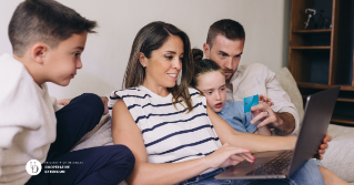 A family together looking at a laptop while one holds a credit card in hand