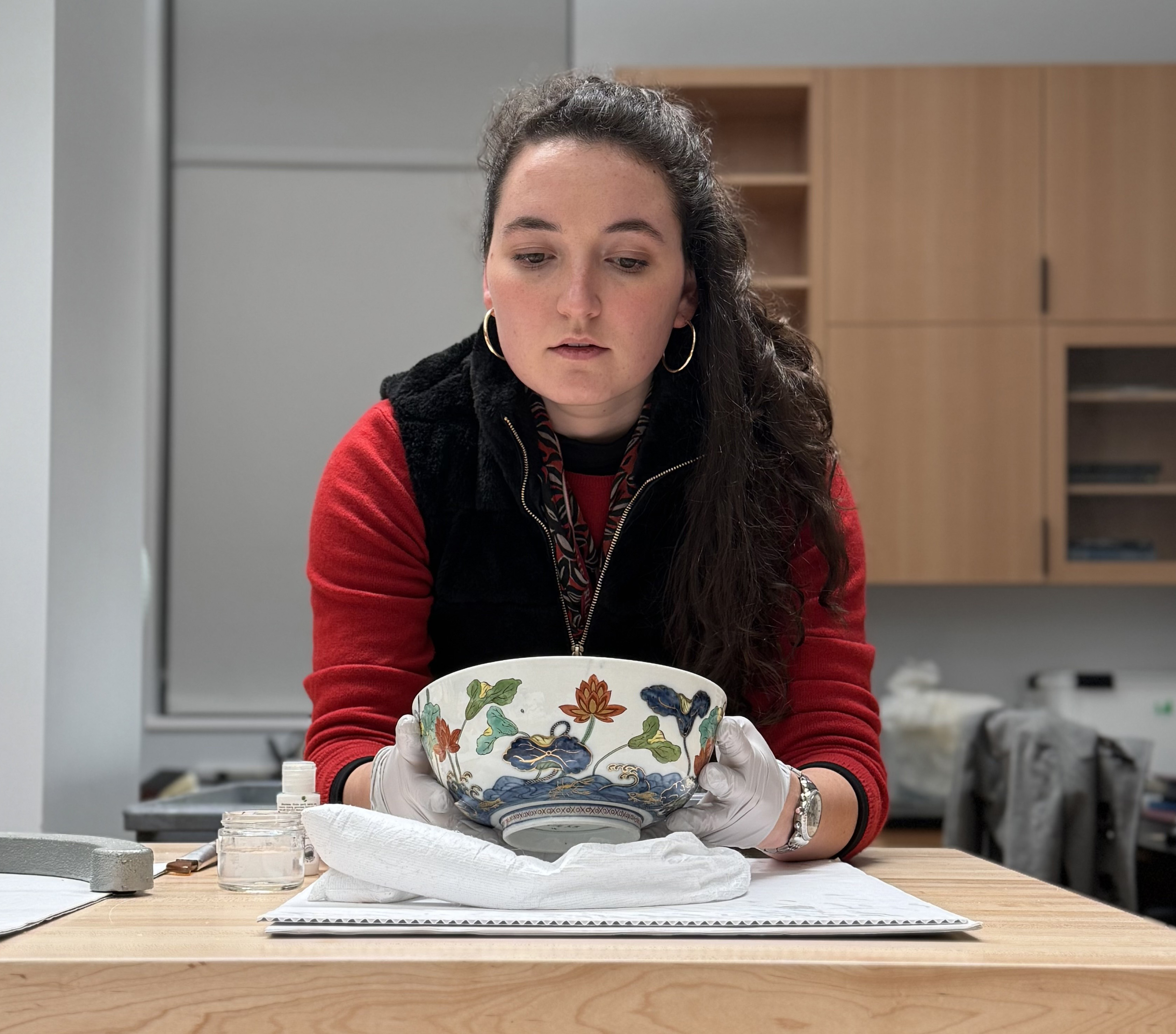 WUDPAC Class of 2025 Fellow Kiki Peters looking at her completed fill (above the red flower) on a Meissen bowl (2016.9.25). 