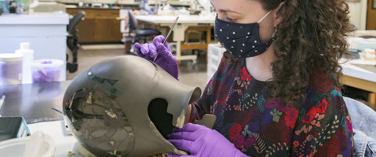 Student working on preserving an old vase