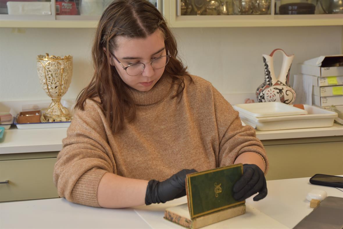 ​Kaitlyn Cannizzo carefully dusts the interior pages of a historical book