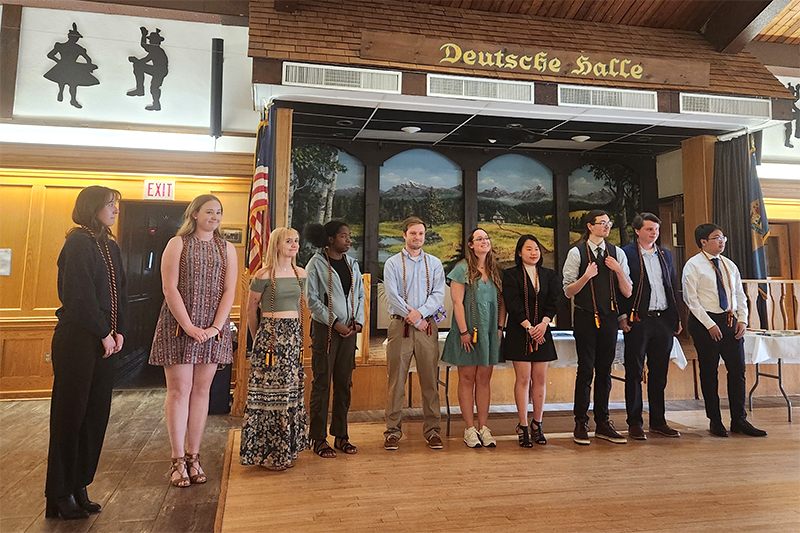 Several students dressed in business attire receive awards inside a large banquet room.