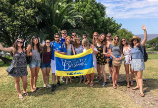 A large group of University of Delaware students in Argentina holding a blue and gold University of Delaware banner