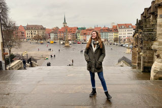 University of Delaware student Rachel Harell stands on stone steps of a historic building overlooking a city square in Leipzig, Germany.