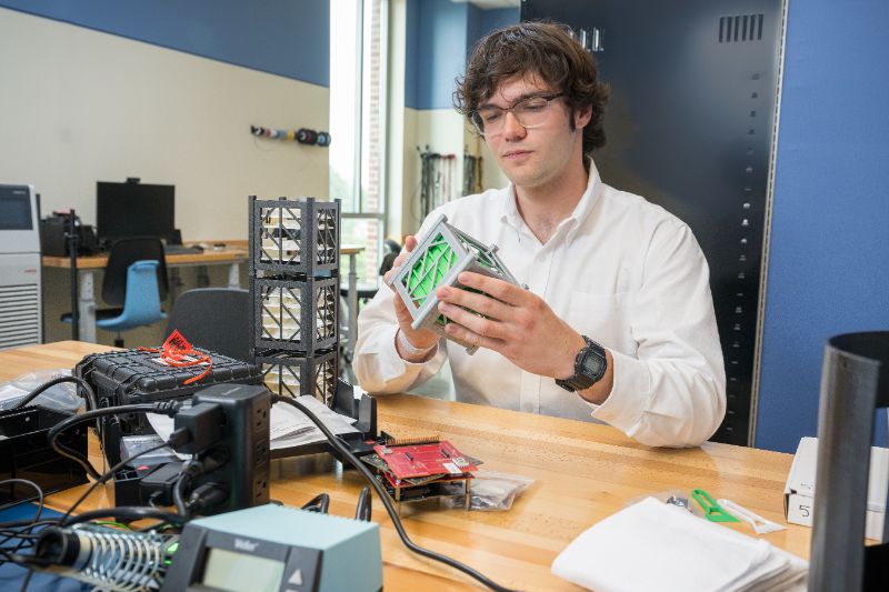 Students working in a lab with a cube satellite