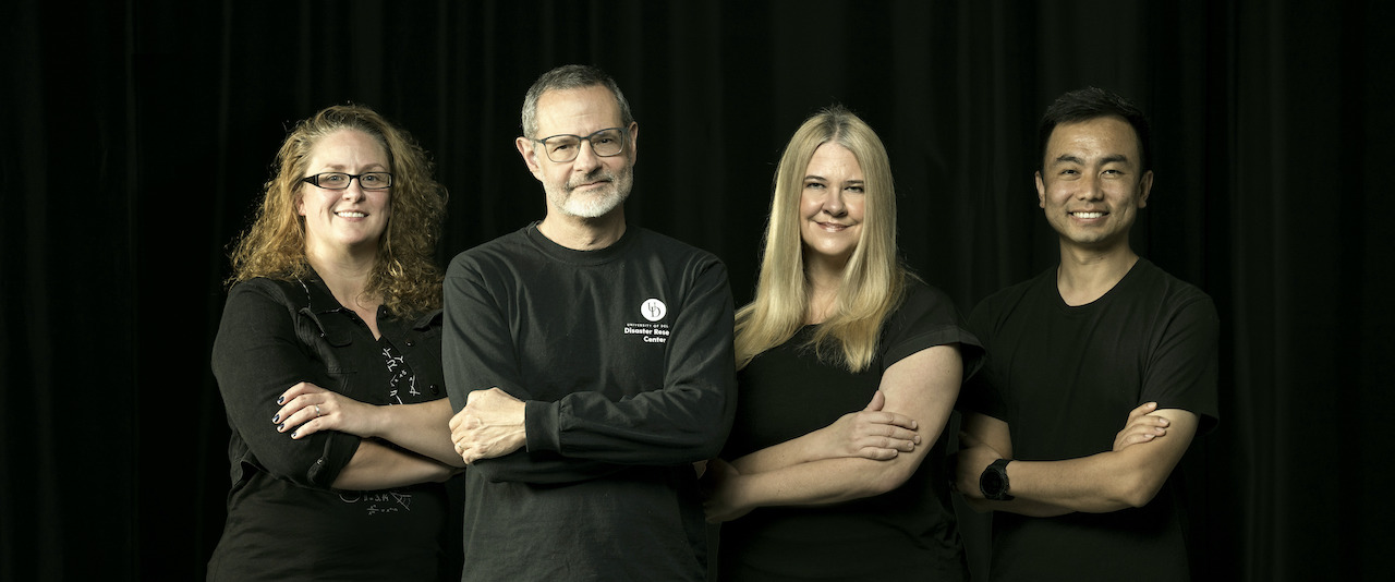 4 people dressed in black side by side crossing their arms