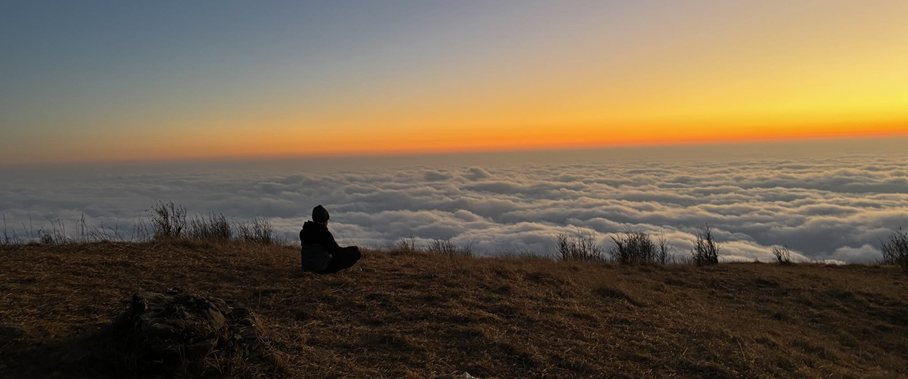 Photo of a person sitting alone watching the sunset