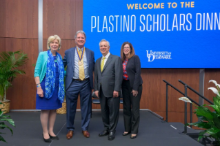 Debra Norris and UD Leadership standing in front of Plastino Scholars Dinner banner