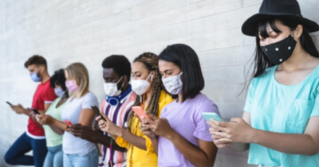 Line of people standing against a wall using their phones wearing masks