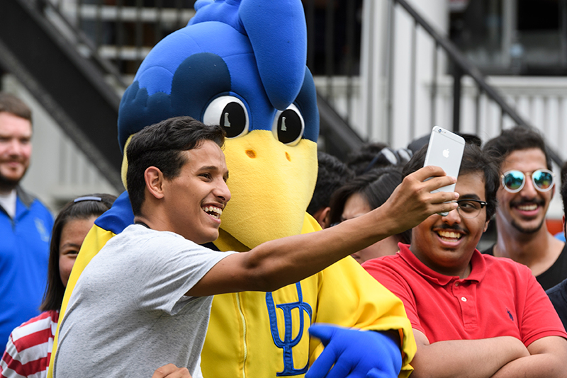 A college student takes a selfie with YoUDee, the University of Delaware's mascot.