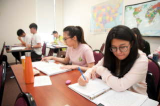 Students in a classroom write notes in notebooks