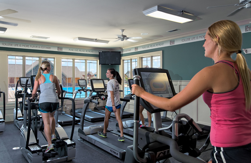 College students exercise on treadmills inside fitness center at apartment complex