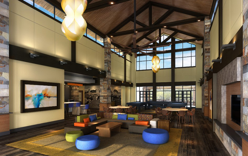 Two-story atrium in apartment complex with colorful furniture, fireplace, and large windows.