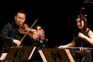 Four musicians on stage playing string instruments, three males and one female