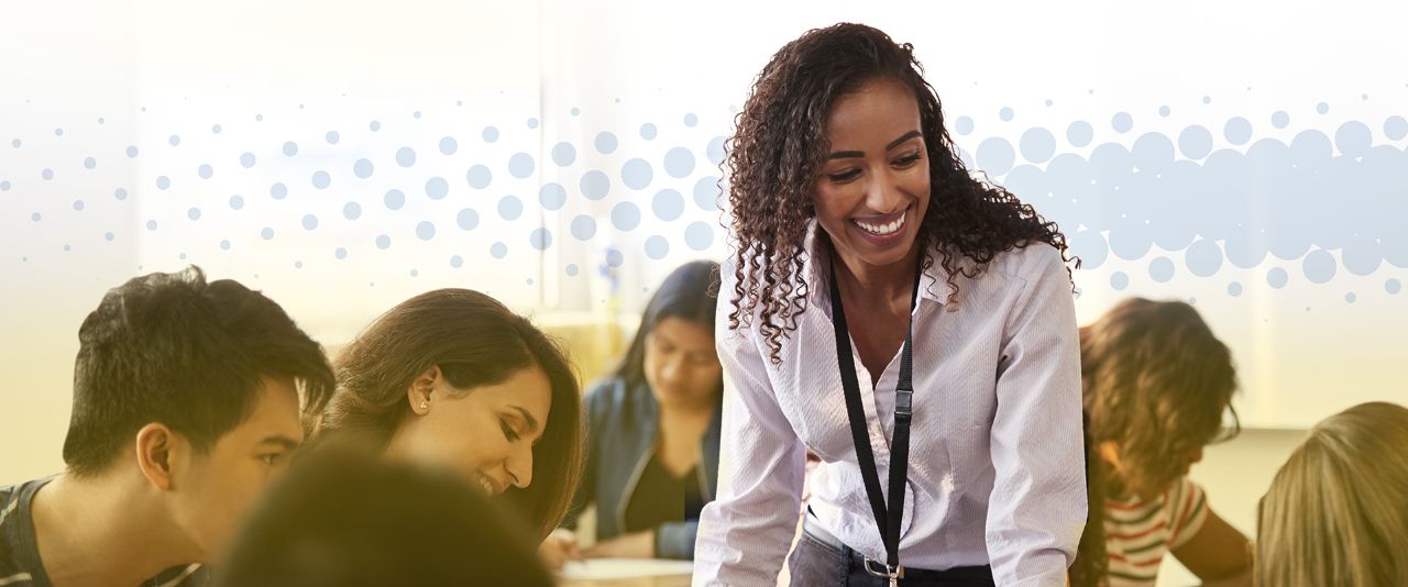 A teacher leaning over a table smiling at engaged students