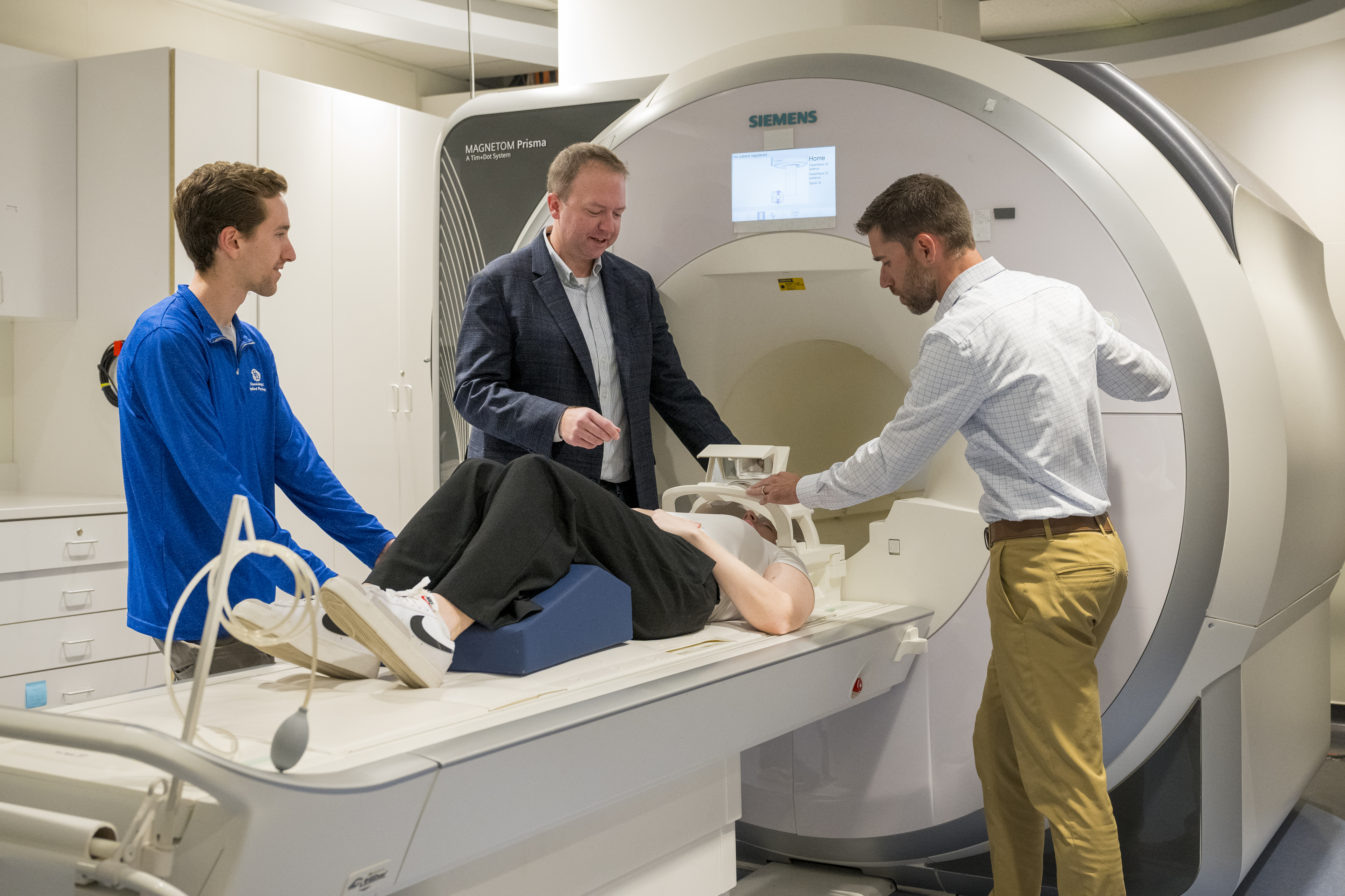 Researchers and a doctoral student pose with a research subject prepared to enter the MRI machine on UD's campus.