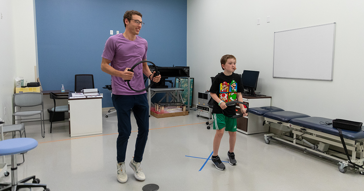 Jacob Corey and a reseach participant play a fitness video game