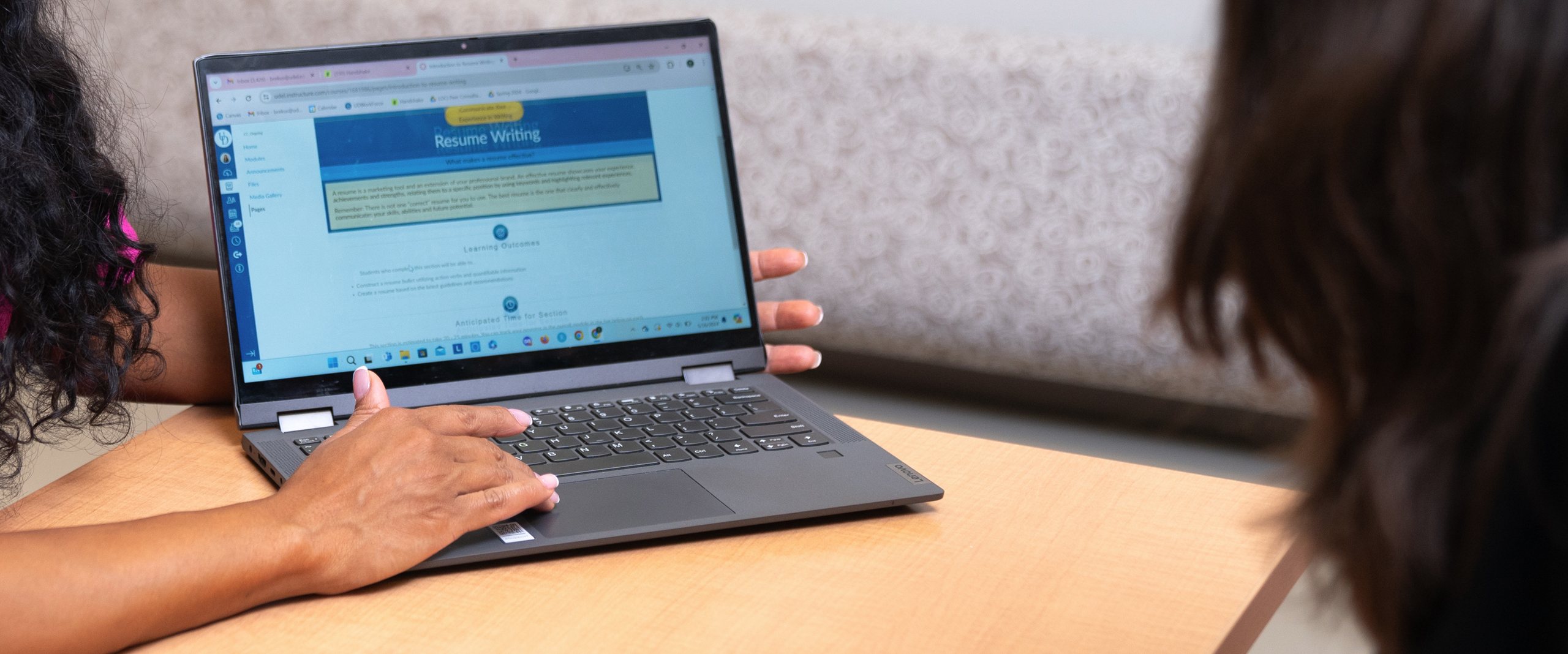 close-up of a laptop displaying a Canvas module while a student looks on