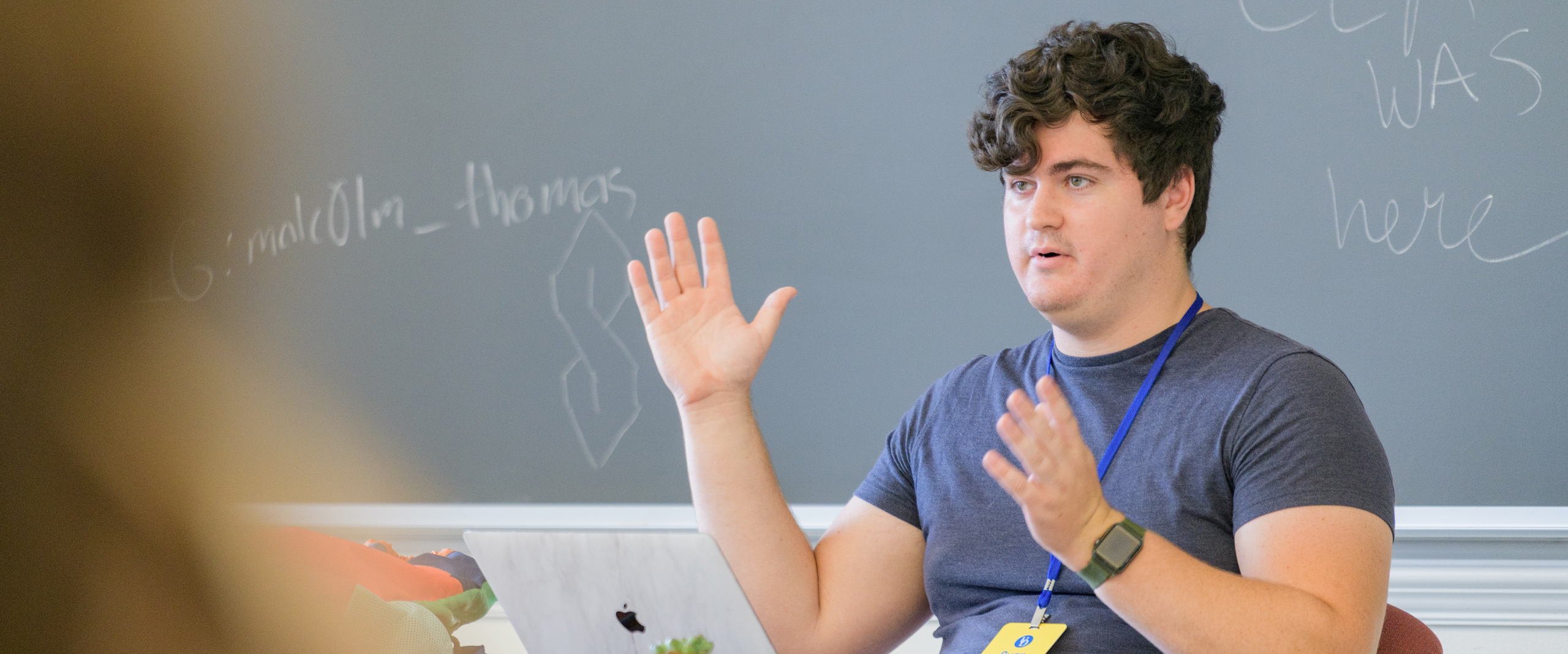 a UD student sits at a desk, instructing a class