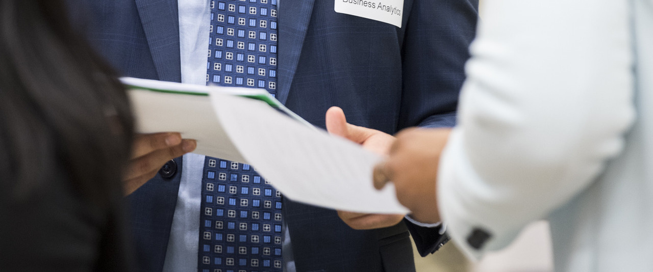 Student handing a copy of their resume to an employer